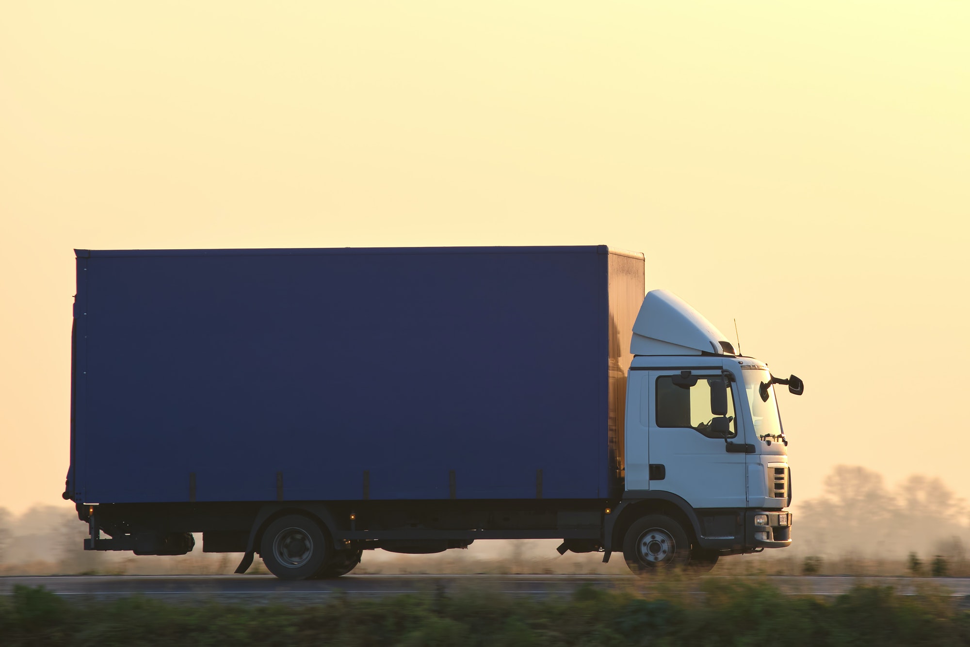 Cargo truck driving on highway hauling goods in evening. Delivery transportation and logistics